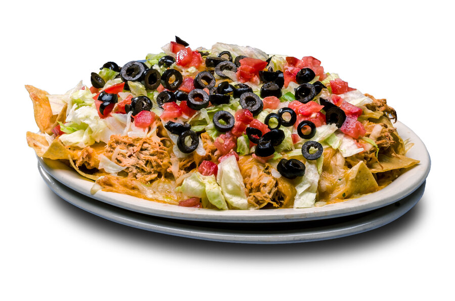 A large pile of tortilla chips and cheese topped with lettuce, tomato, ripe olives, sour cream, salsa and your choice of bean, chicken, pork or beef.